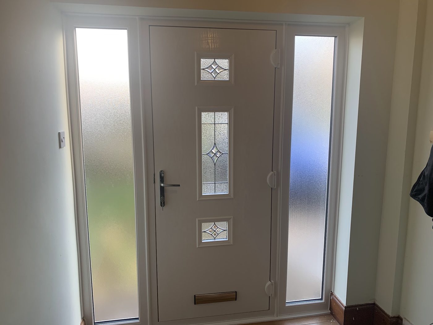 A taupe composite door with frosted side lights, seen from inside the hall