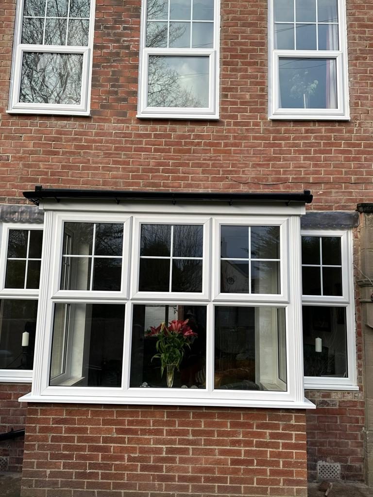 A white bay window on a brick house