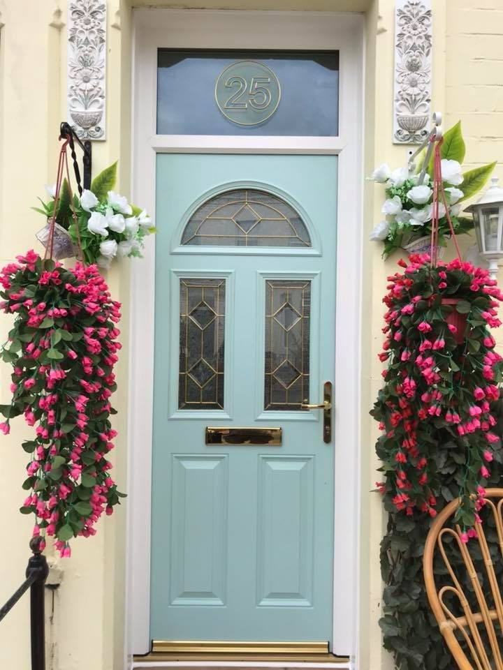 A duck-egg blue front door with hanging flower baskets either side